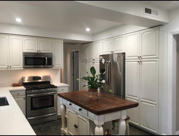 Kitchen showing stainless appliances, full height white cabinetry, and butcher block island