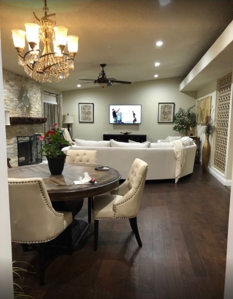 Living and dining area with crystal chandelier, stone fireplace, hardwood floors, and open plan layout