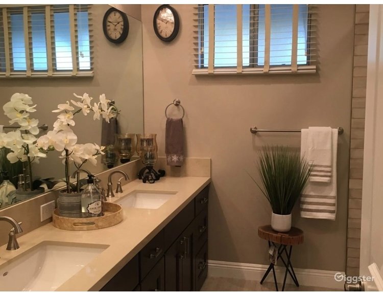 Beautifully styled master bathroom with double vanity, white orchids and spa towels