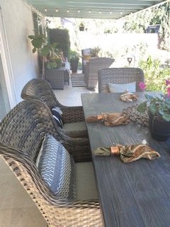 Wicker dining chairs around a large outdoor table during the day