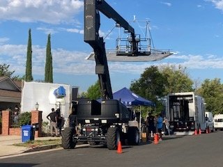 Large camera crane rig deployed on the street in front of the property during a commercial shoot
