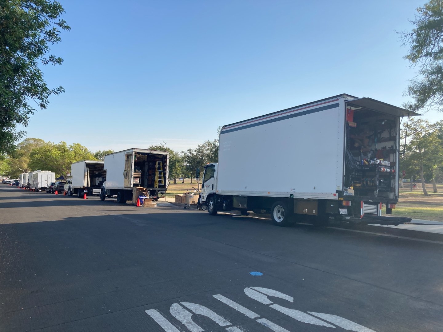 Multiple equipment trucks staged at nearby park for the production