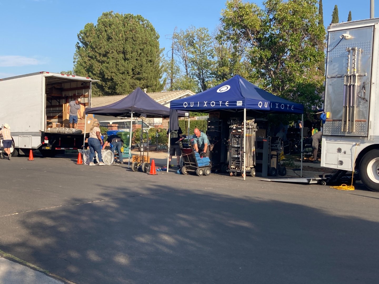 Quixote production tents with crew unloading equipment from trucks during early morning setup